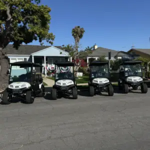 Four identical white Nado Karts electric golf carts parked in a row on a street in Coronado.